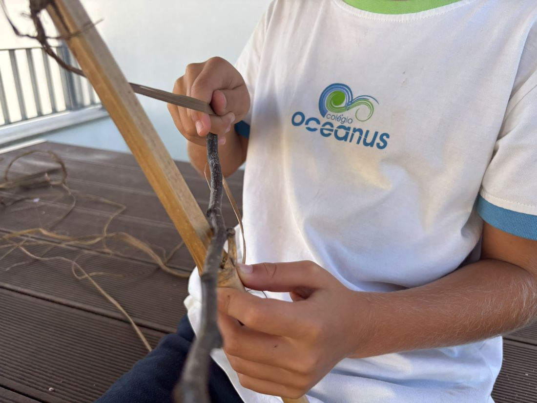 Aluno a unir uma vara à cana com fibras vegetais
