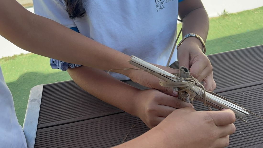 Alunos a atar canas com fibras vegetais